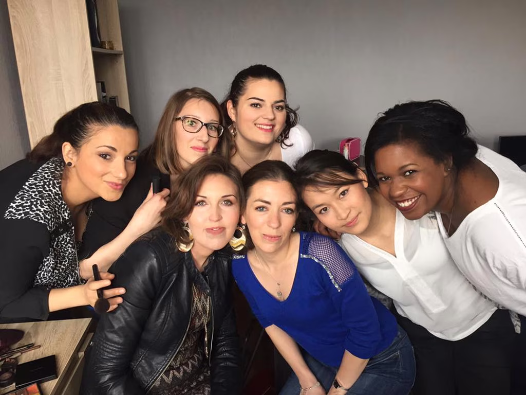 Un rassemblement joyeux d'amies aux sourires éclatants, chacune arborant un look maquillage qui révèle son style personnel, symbolisant la diversité et la camaraderie